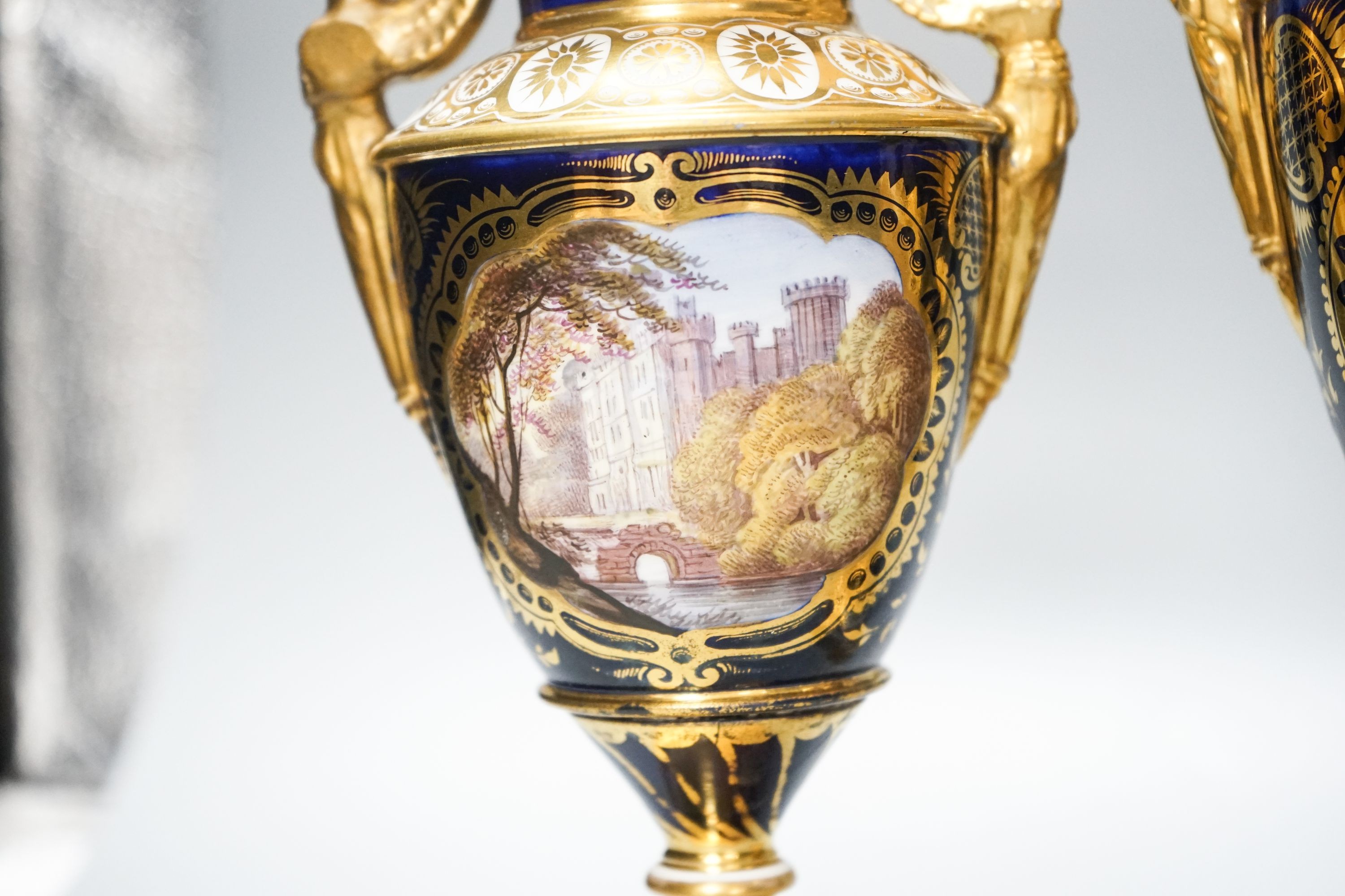 A garniture of three early 19th century English porcelain vases, c.1815-20, each painted with topographical views, tallest 26cm